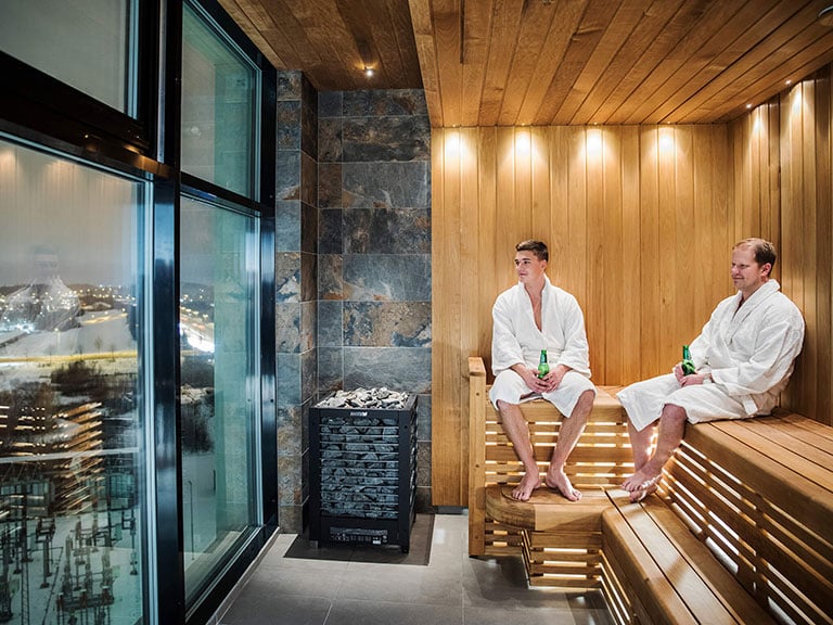 Två män i hotellets bastu som dricker öl och tittar ut över Uppsala