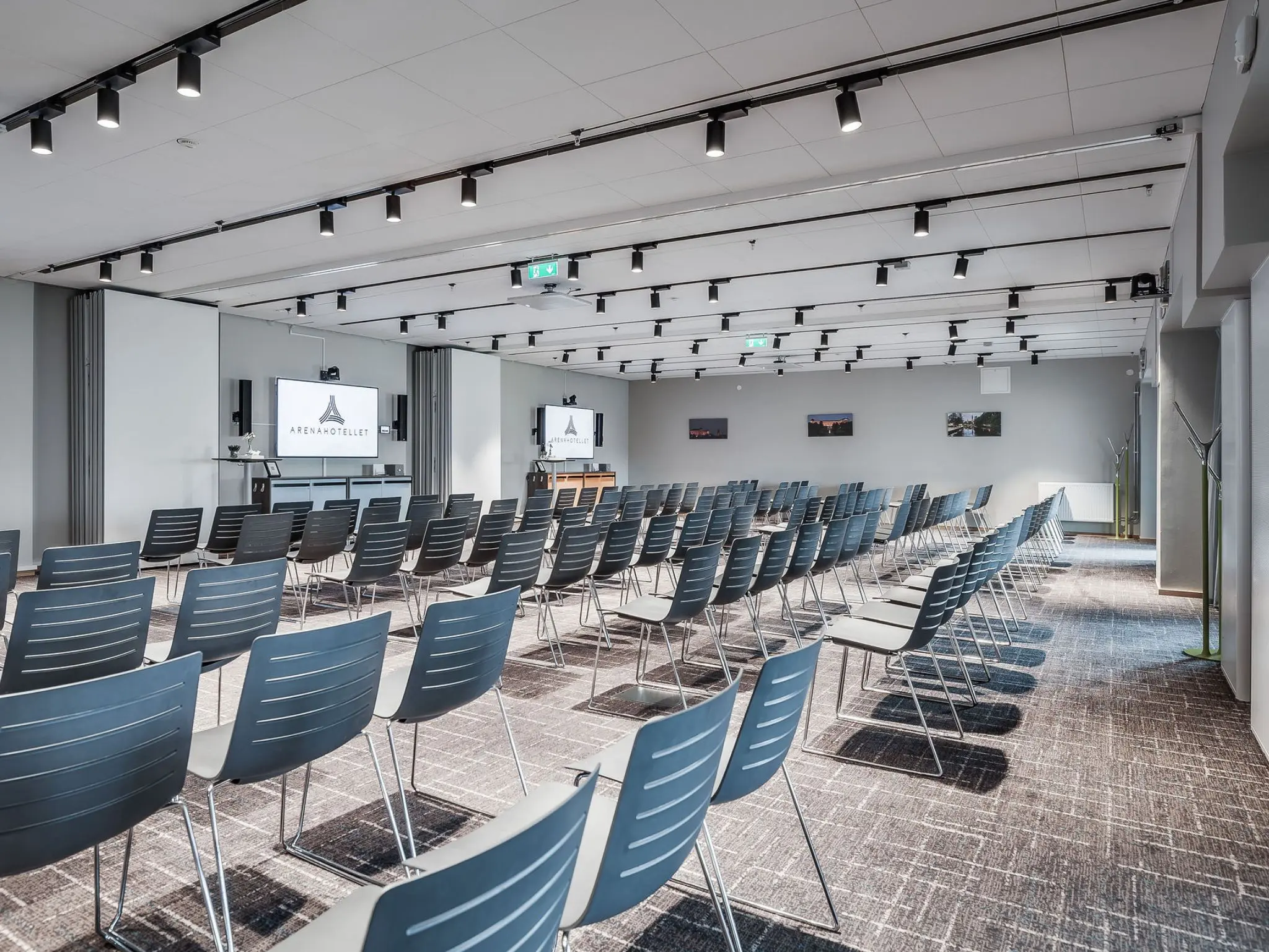 Stort konferensrum med flera rader stolar och tre skärmar