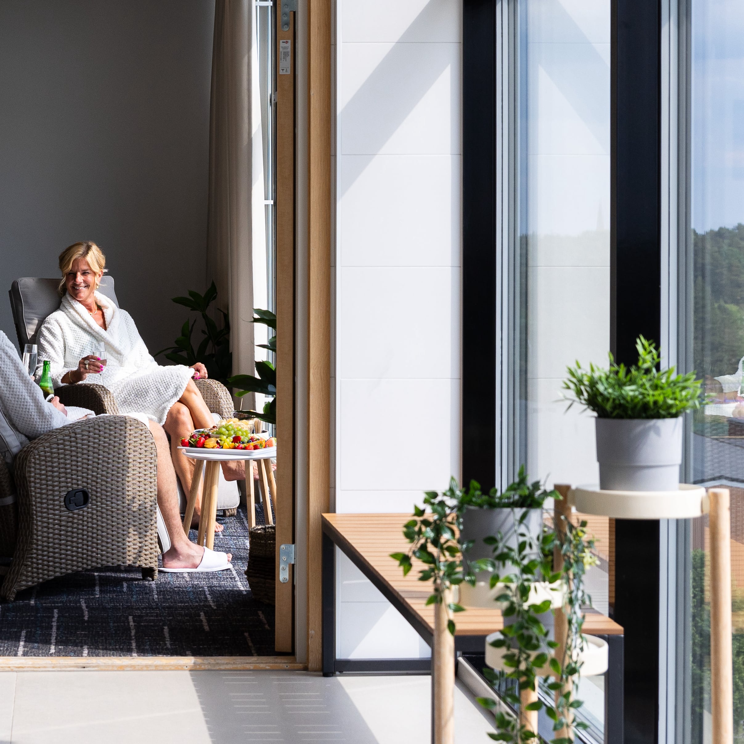 Två besökare i morgonrock som sitter i relaxavdelningen och tittar ut över Uppsala