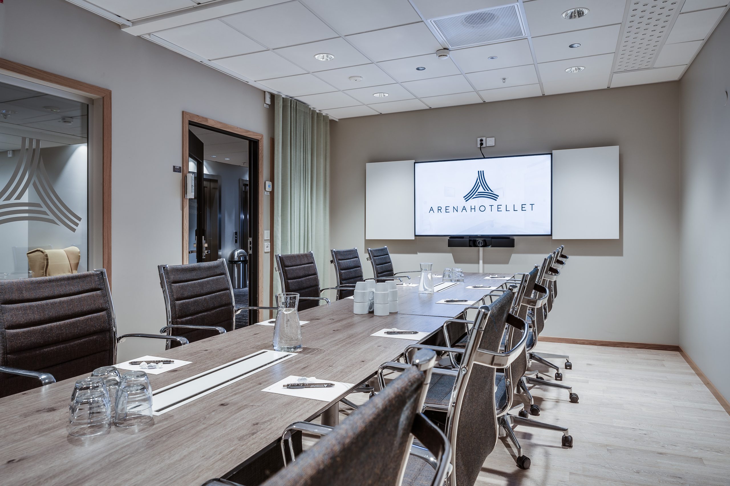 Conference room with a long table and a large screen at one end