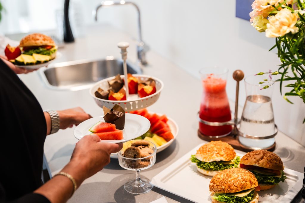 Folk som plockar åt sig frukt och fika från en buffe
