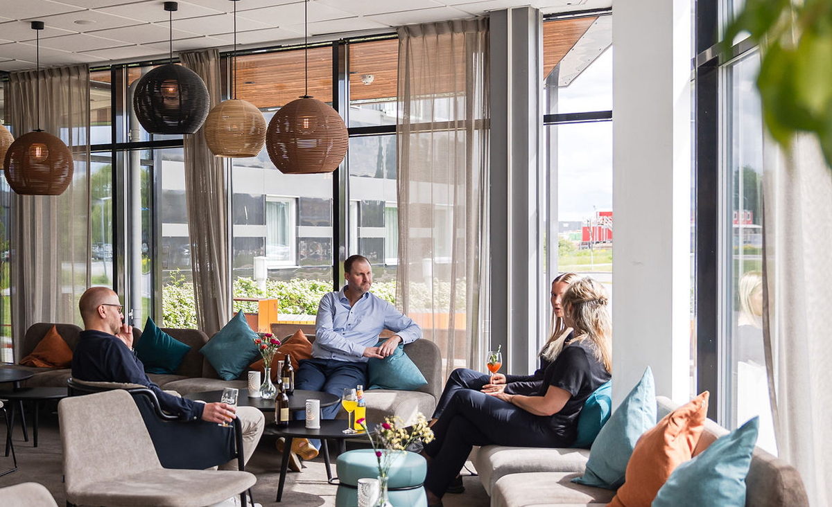 En grupp som sitter i hotellets lounge och pratar och dricker