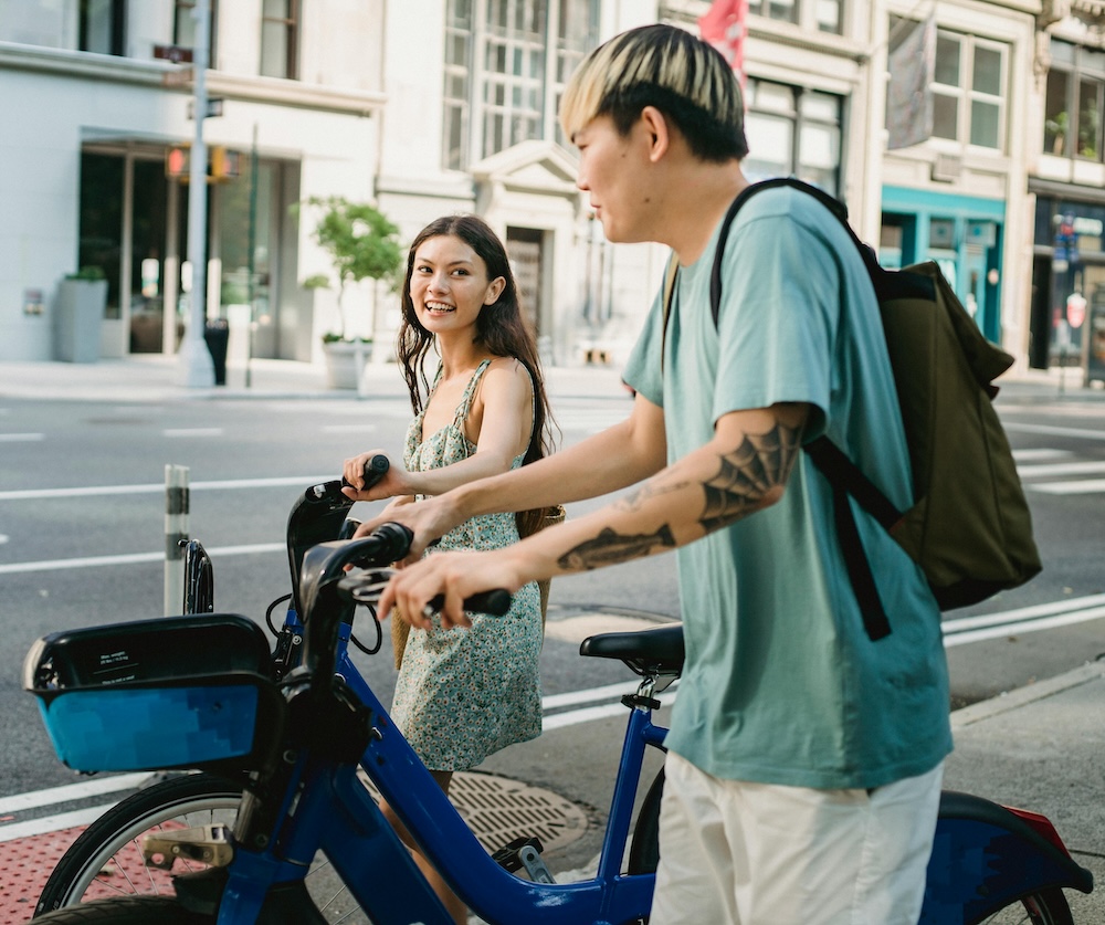 Två personer i stan som leder sina cyklar och pratar med varandra