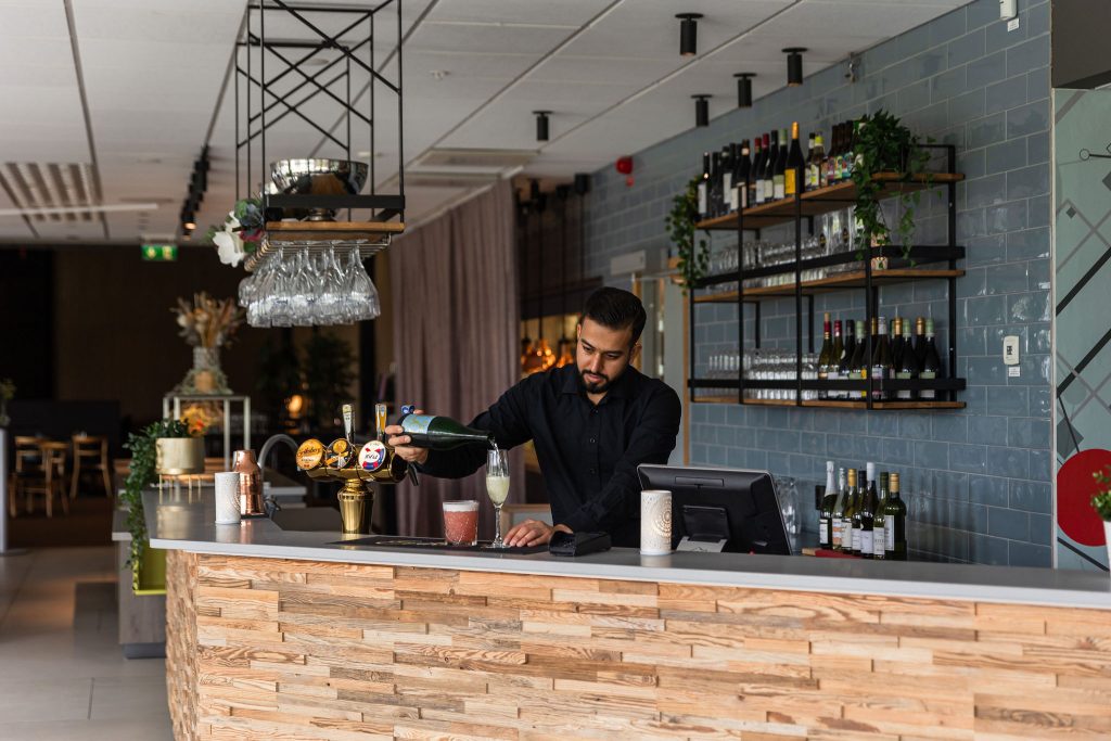 Bartender håller upp ett glas mousserande vin i baren