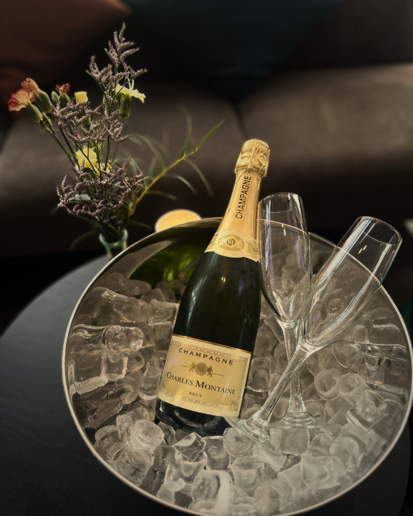 En flaska champagne som ligger på kylning på is tillsammans med två glas