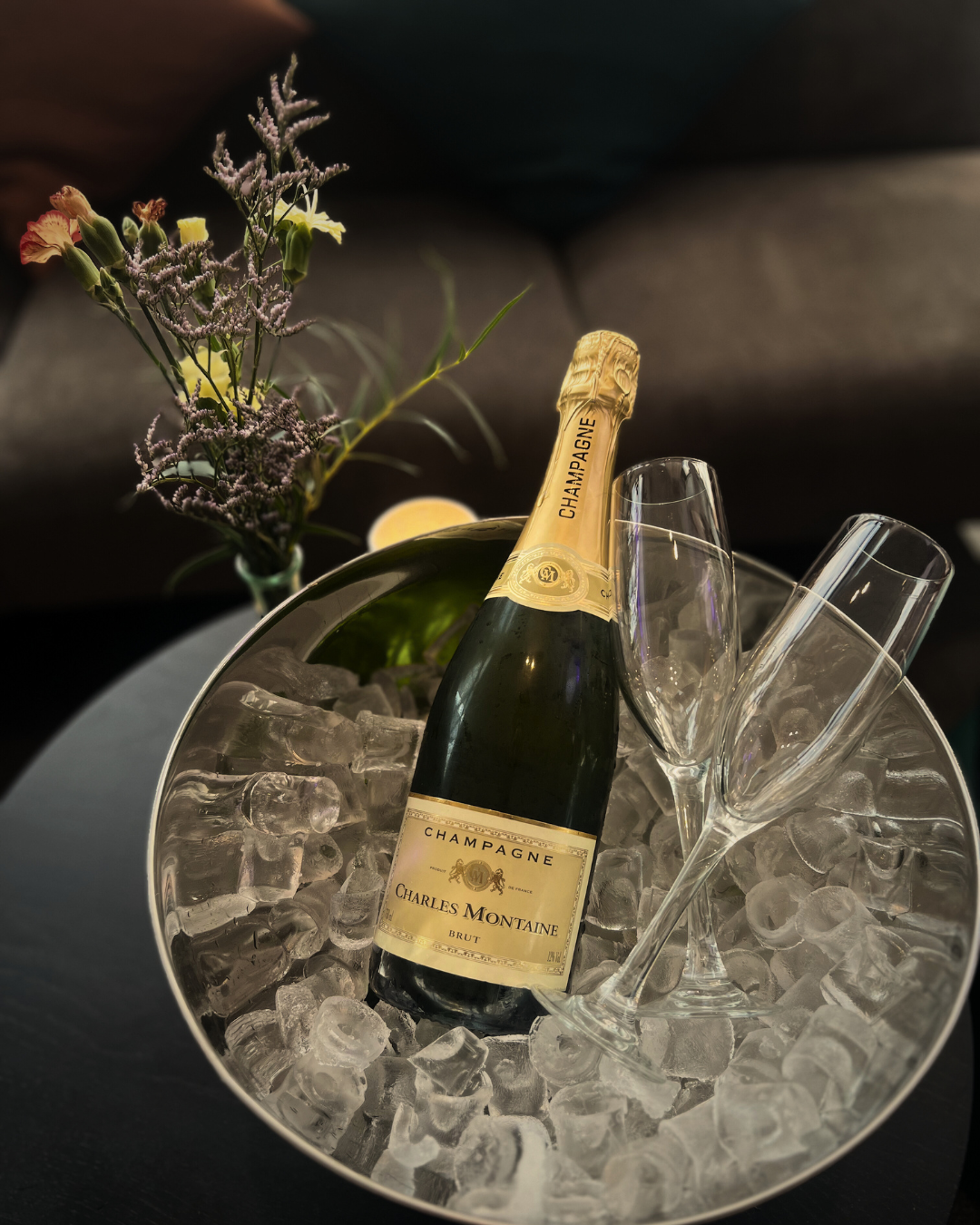 En flaska champagne som ligger på kylning på is tillsammans med två glas