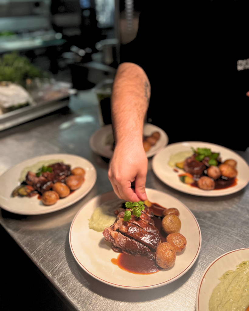 Kock som lägger upp mat på fyra tallrikar